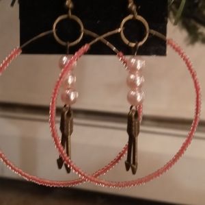 Beaded pink hoop hook earring with arrow inside.
